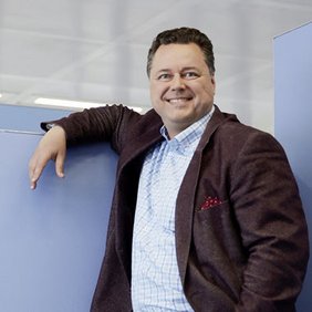 Wolfgang Kräußlich steht in einem Büro mit einem Arm an einen Raumtrenner gelehnt.