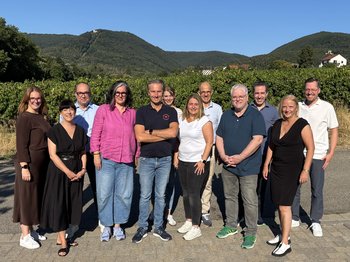 Gruppenbild der Kommission, im Hintergrund Berge und blauer Himmel
